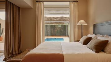 Une chambre d’hôtel avec un lit, une lampe de chevet, une vue sur une piscine et un cactus à l’extérieur.