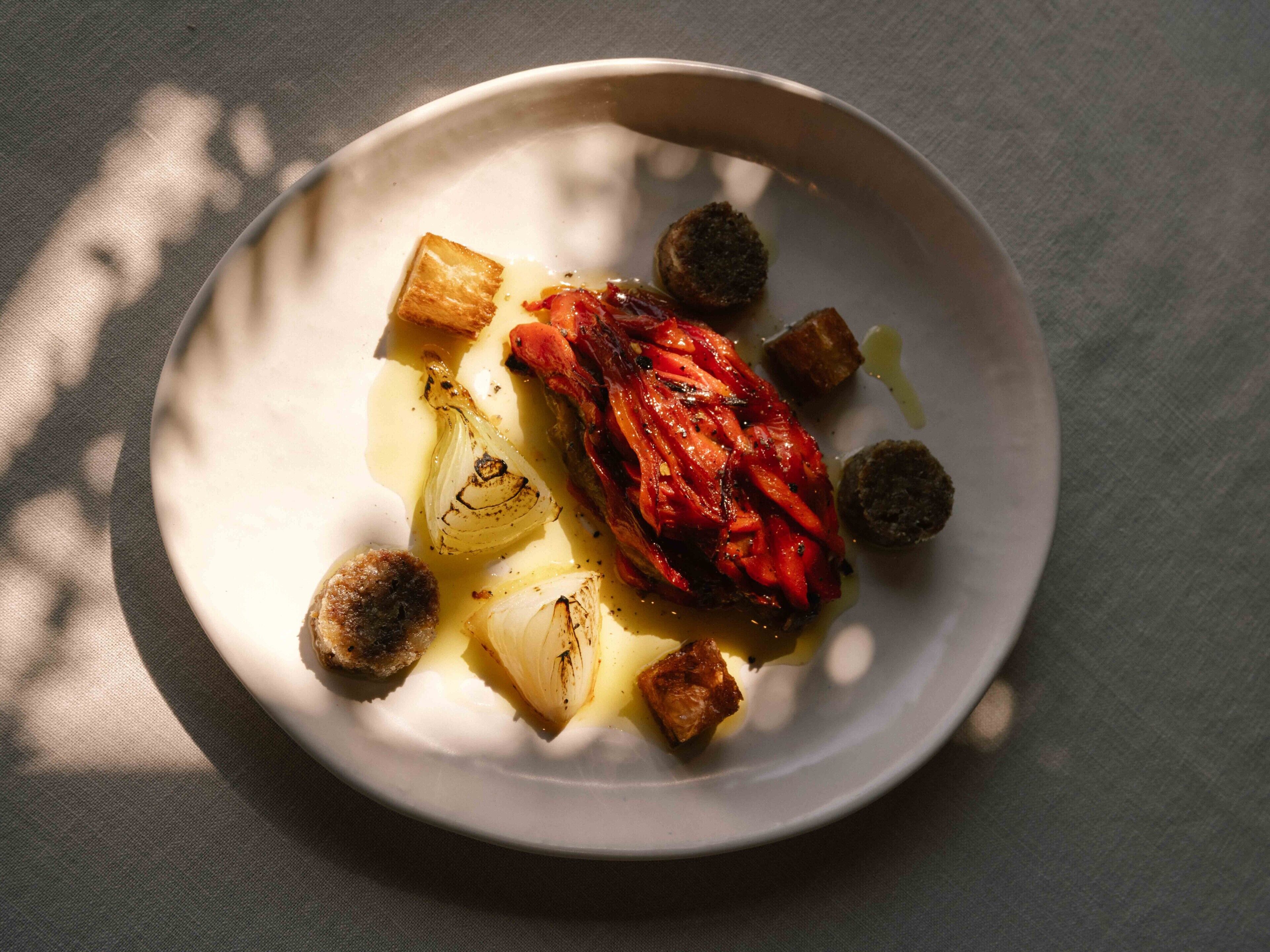 A plate with roasted vegetables and a piece of meat on a white plate.