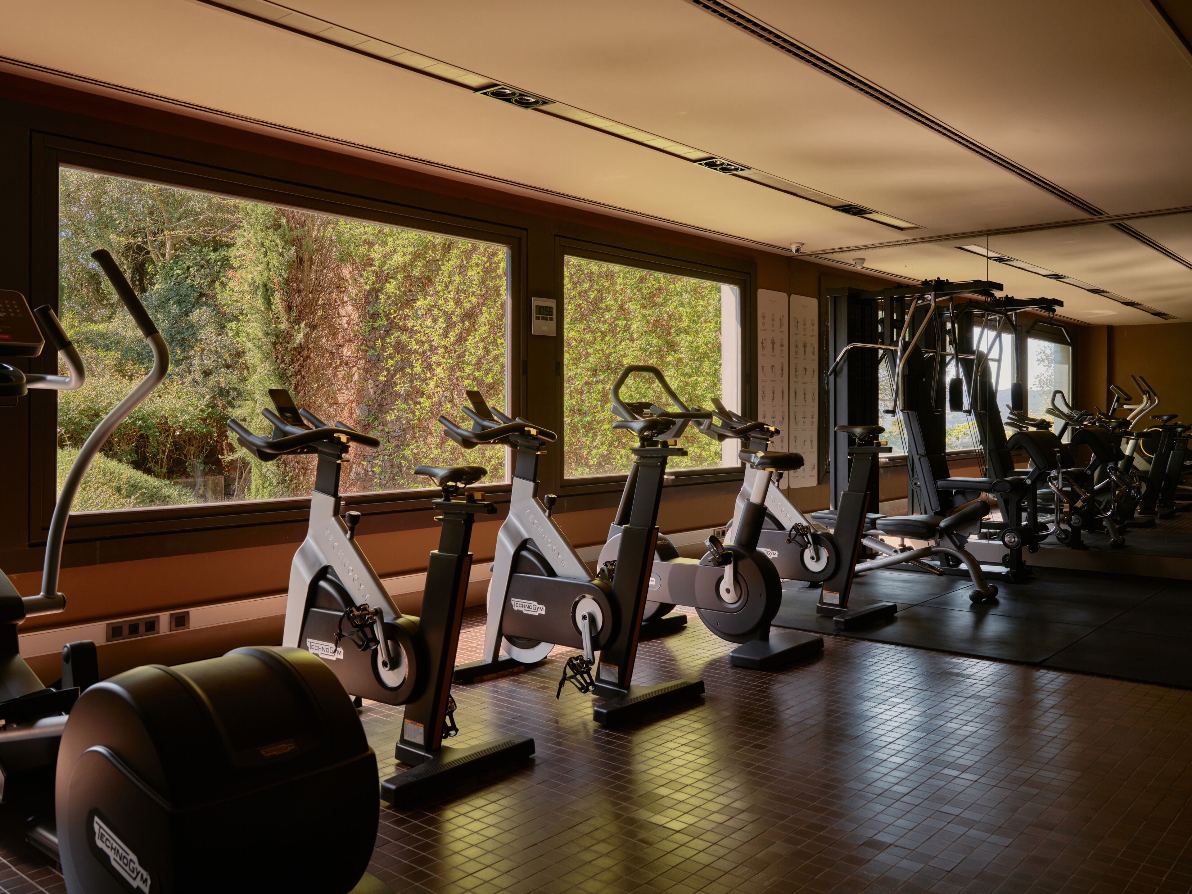Un gimnasio con bicicletas estáticas, elípticas y equipo de pesas.