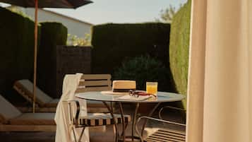 An outdoor patio with a round table, two chairs, a bench, and an umbrella.