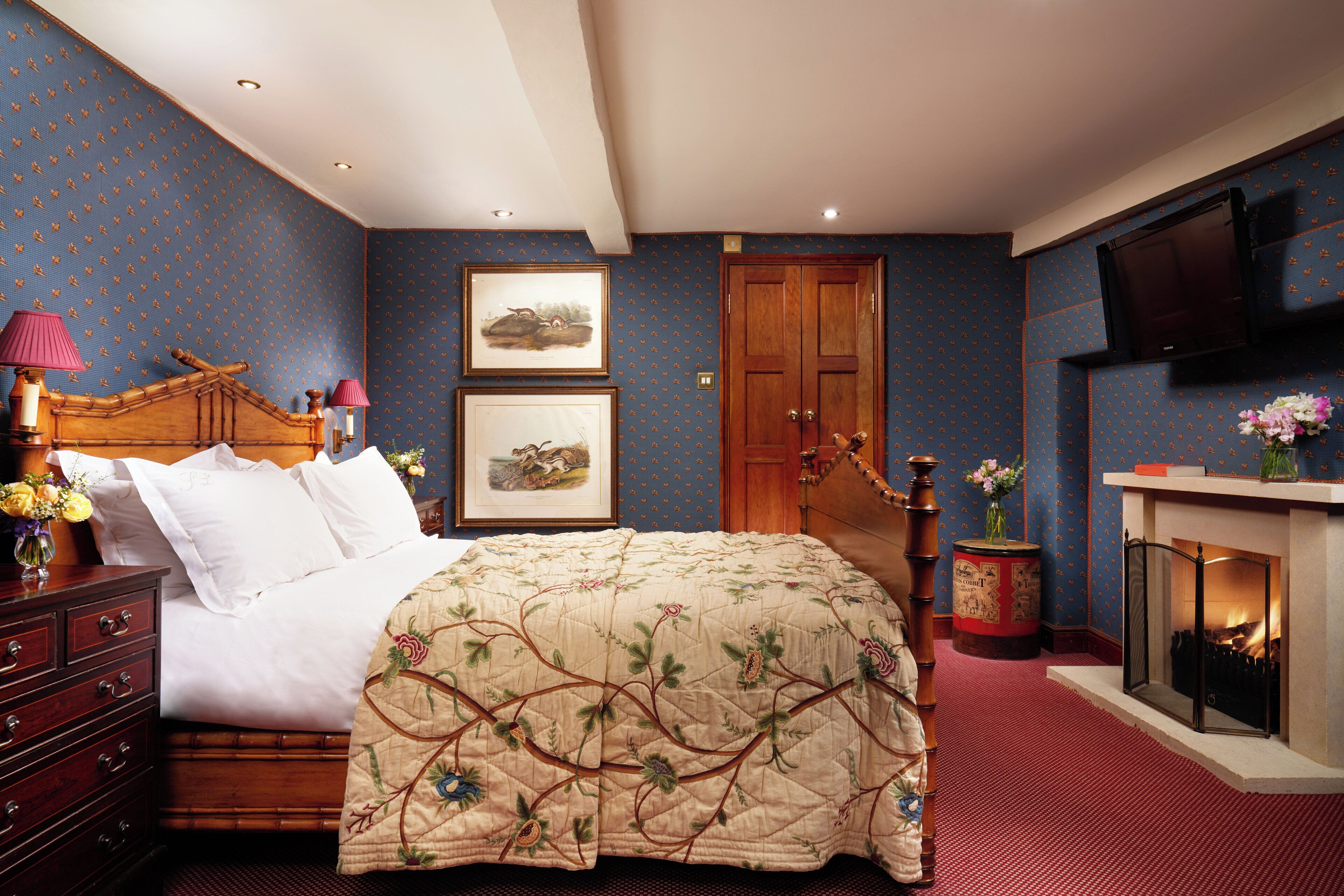A bedroom with a wooden bed, a fireplace, and a television mounted on the wall.