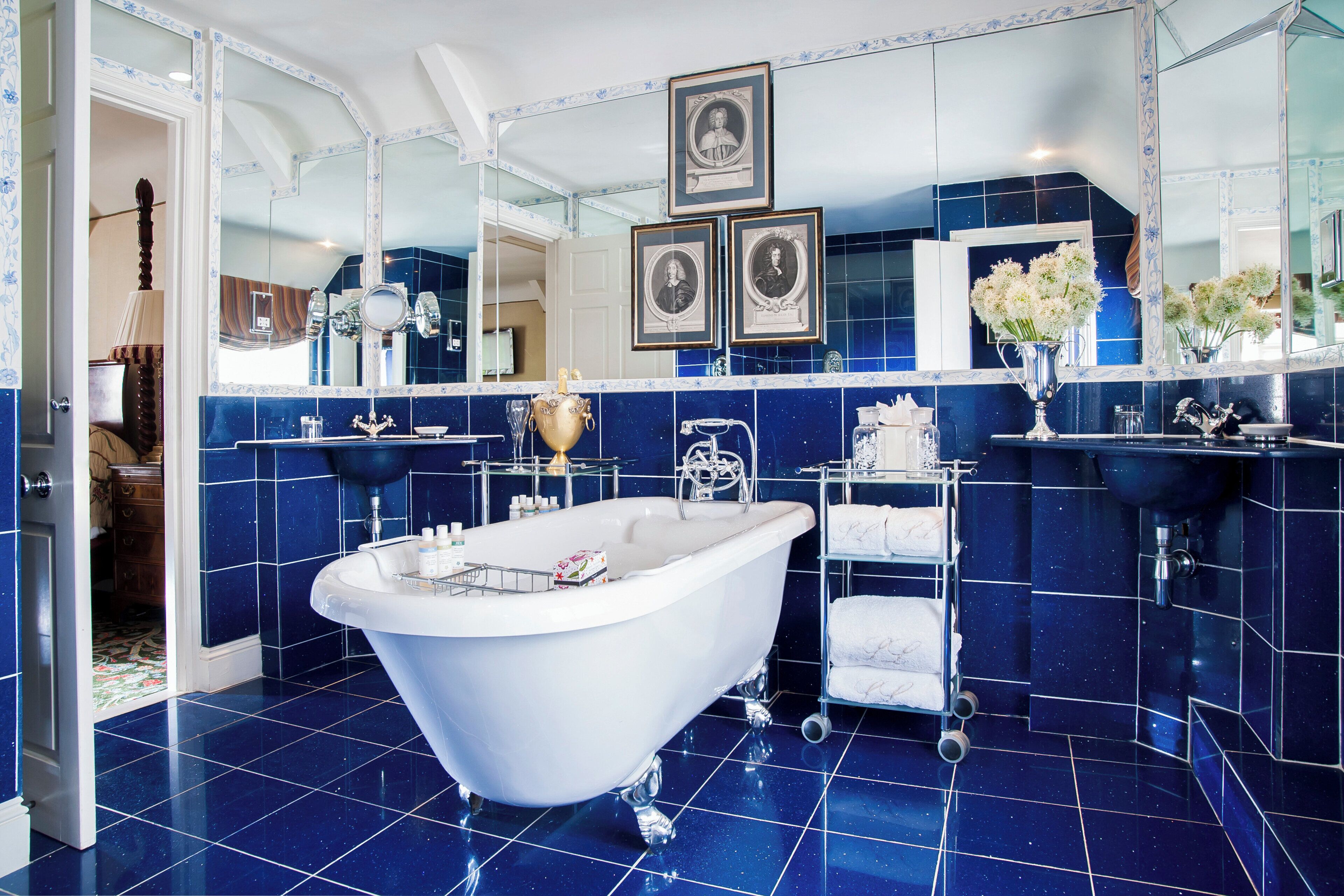 A bathroom with a freestanding bathtub, a vanity with a mirror, and a wall-mounted shelf with towels.