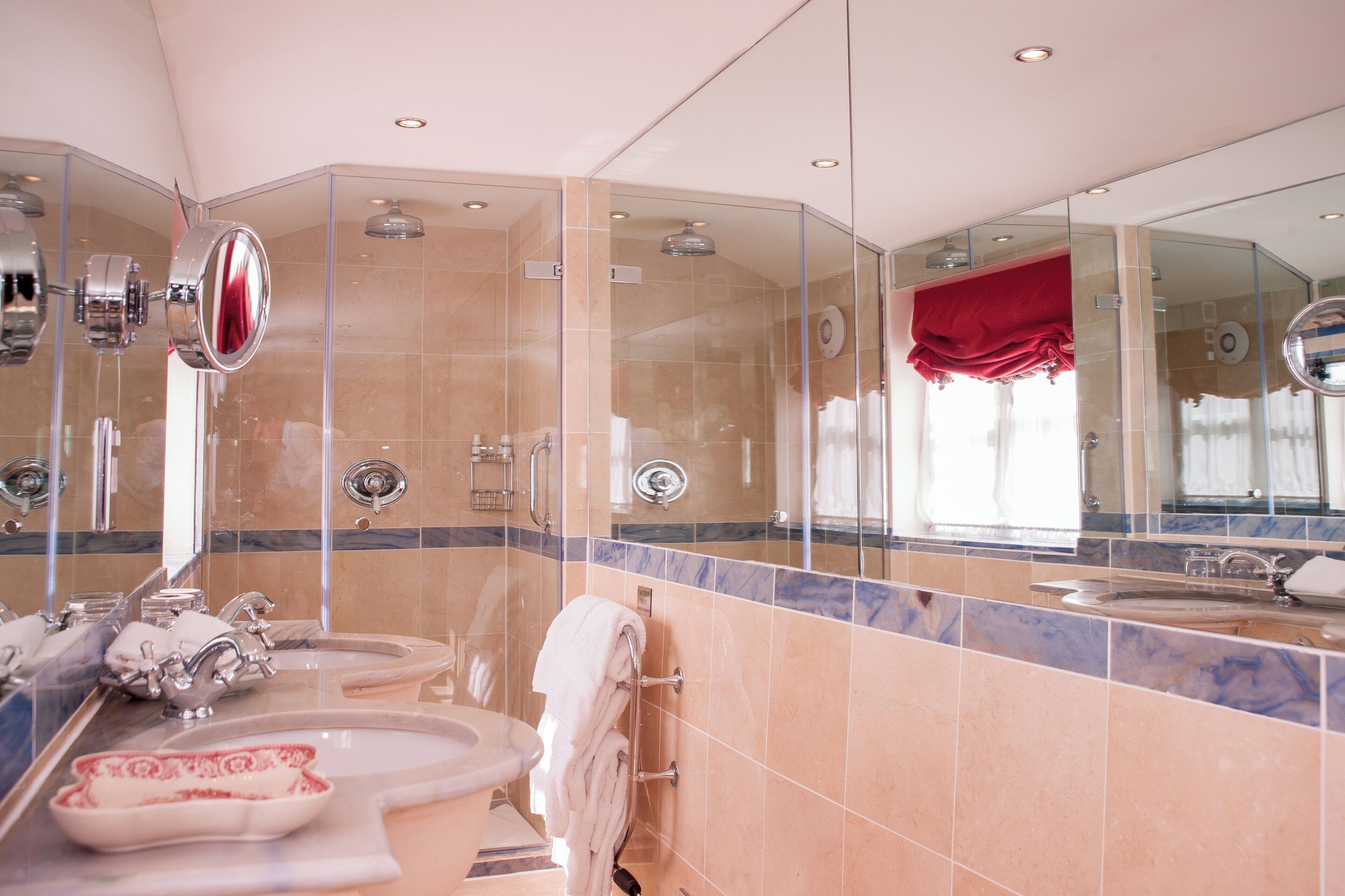 Un baño moderno con ducha de vidrio, tocador con lavamanos y un espejo grande.