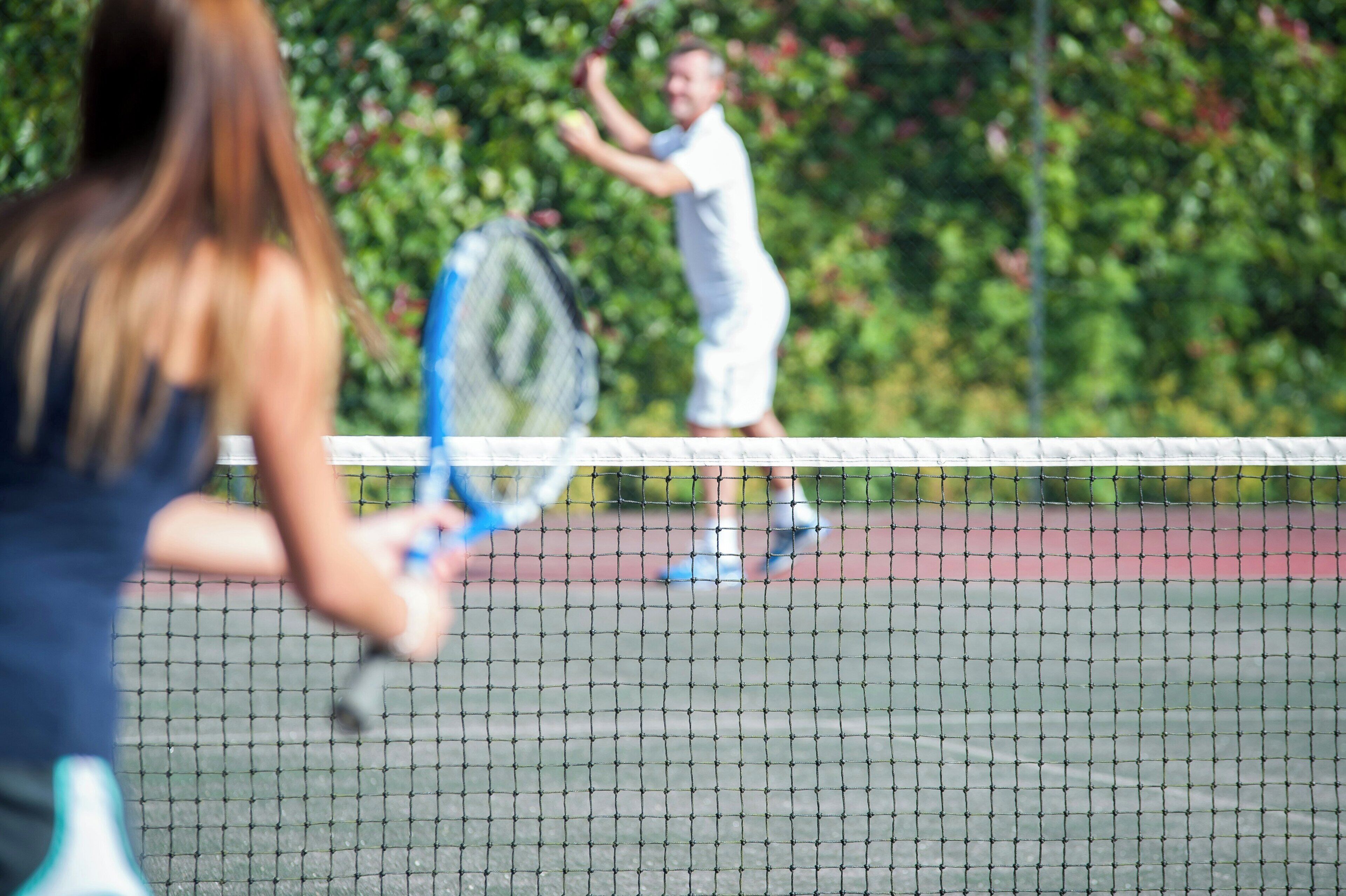A tennis court with a net in the foreground.