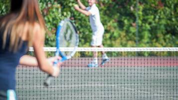 A tennis court with a net in the foreground.