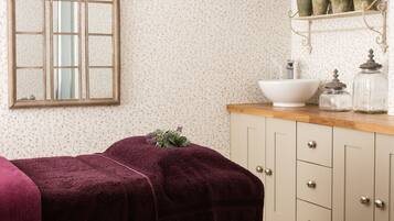 Classic design with a large arched mirror, wooden vanity, and floral-patterned wallpaper.