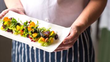 Una persona sostiene un plato blanco rectangular con una ensalada colorida.