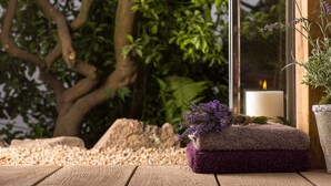 A wooden table with a candle, a lavender plant, and a small rug.