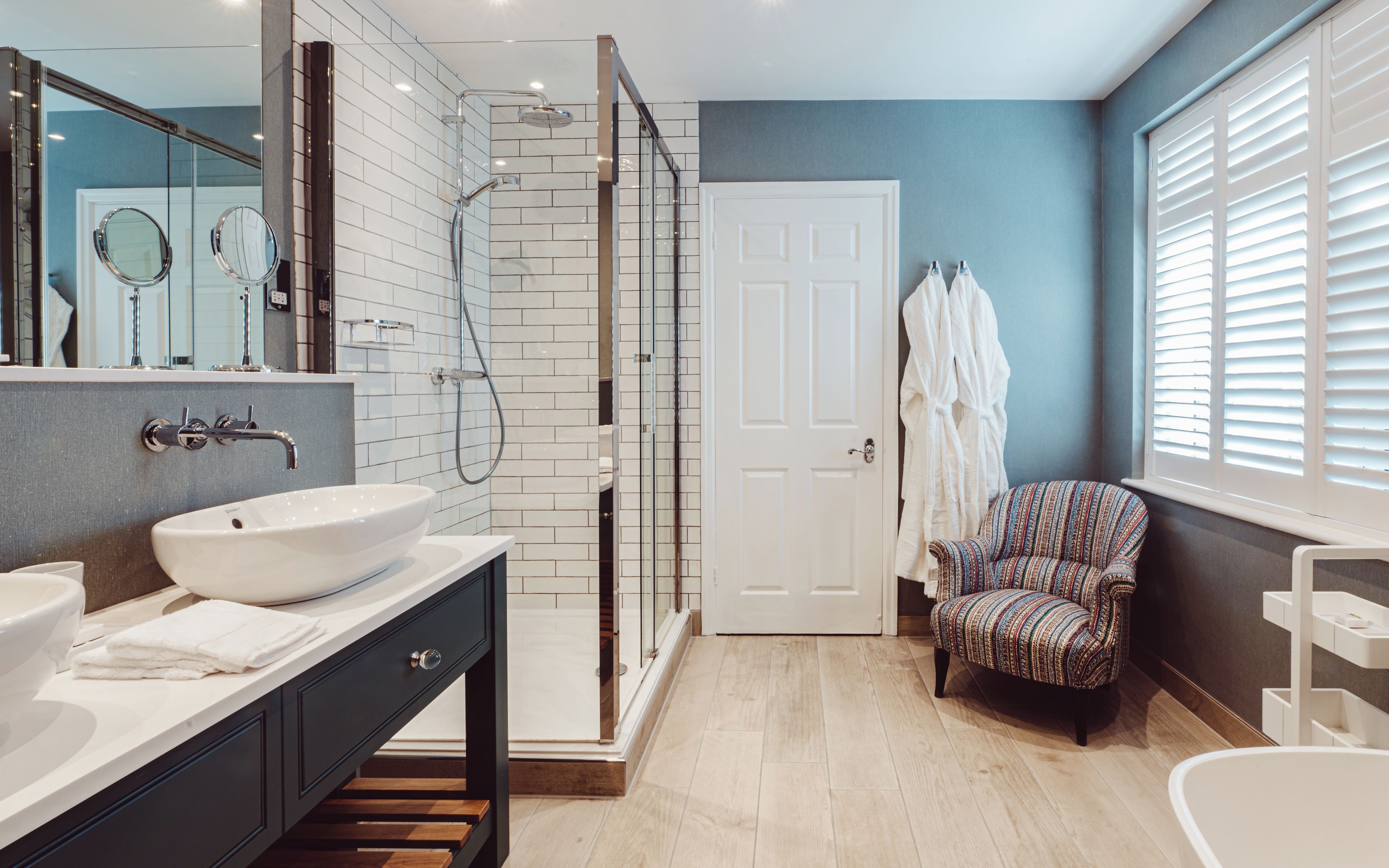 Un baño moderno con un lavamanos grande, ducha a ras de suelo y una silla.