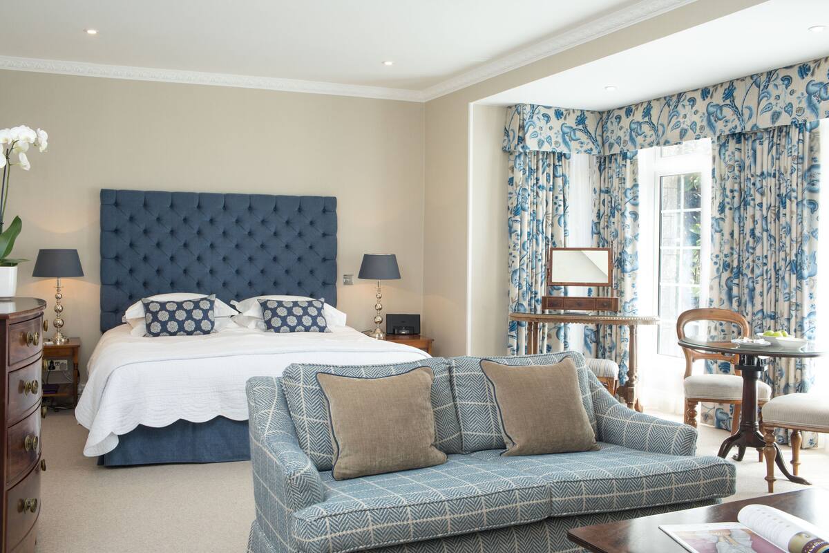 A bedroom with a large bed, a sofa, a dresser, and a table with chairs.