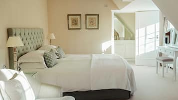 A bedroom with a large bed, a desk, and a chair. There are two framed pictures on the wall.