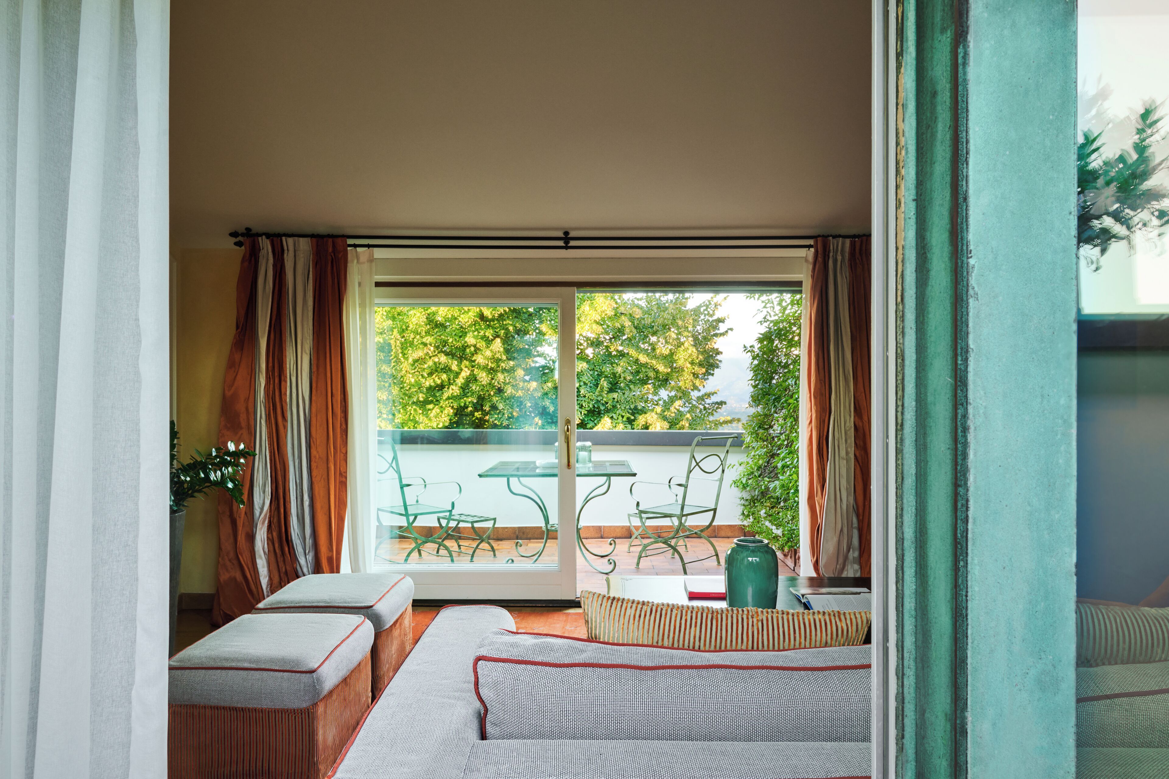 A balcony with a glass door, a sofa, and a table with chairs.