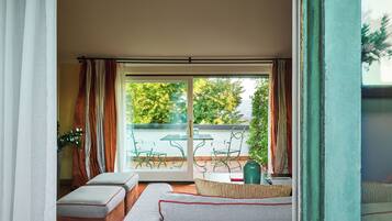 A balcony with a glass door, a sofa, and a table with chairs.