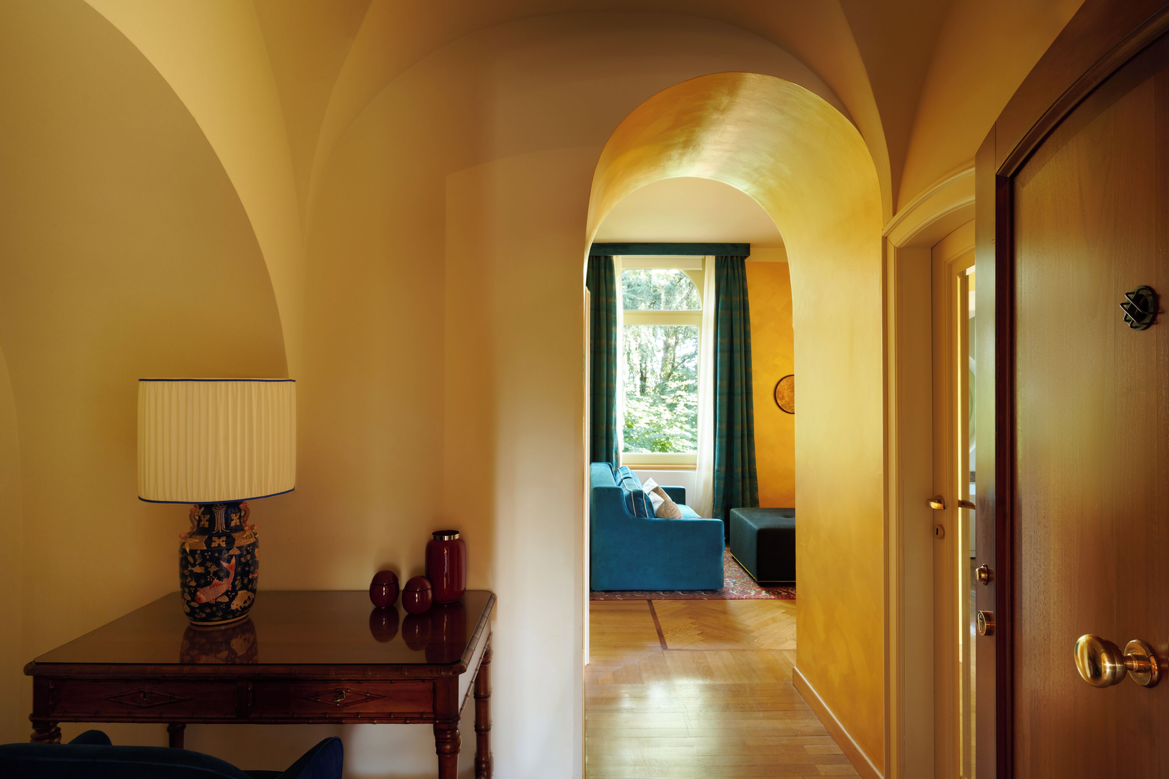 Ein Innenbereich, eine Diele mit einem Holztisch, einer Lampe und einem blauen Sofa im Hintergrund.