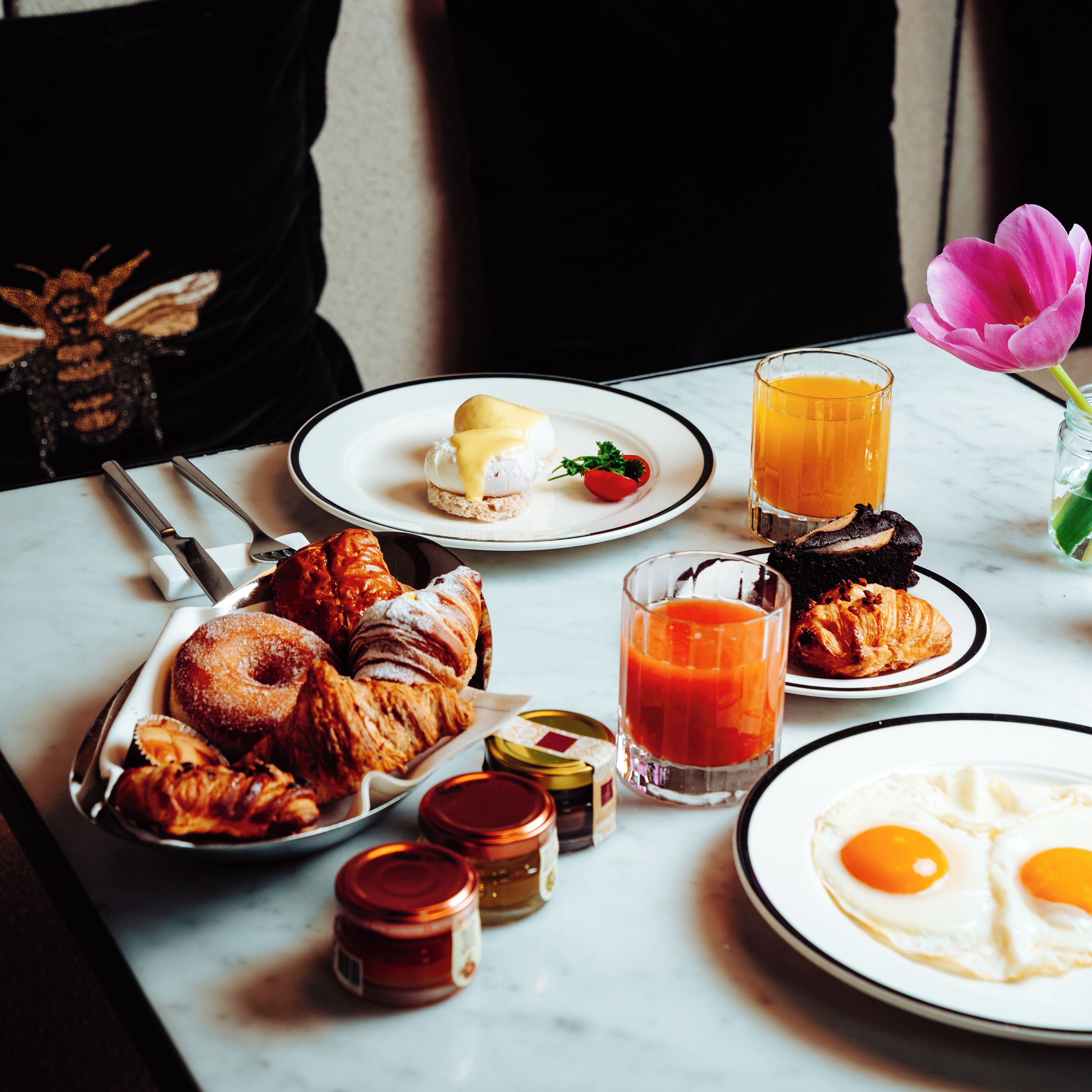 Una mesa de desayuno con pasteles, huevos, jugo y salsas.