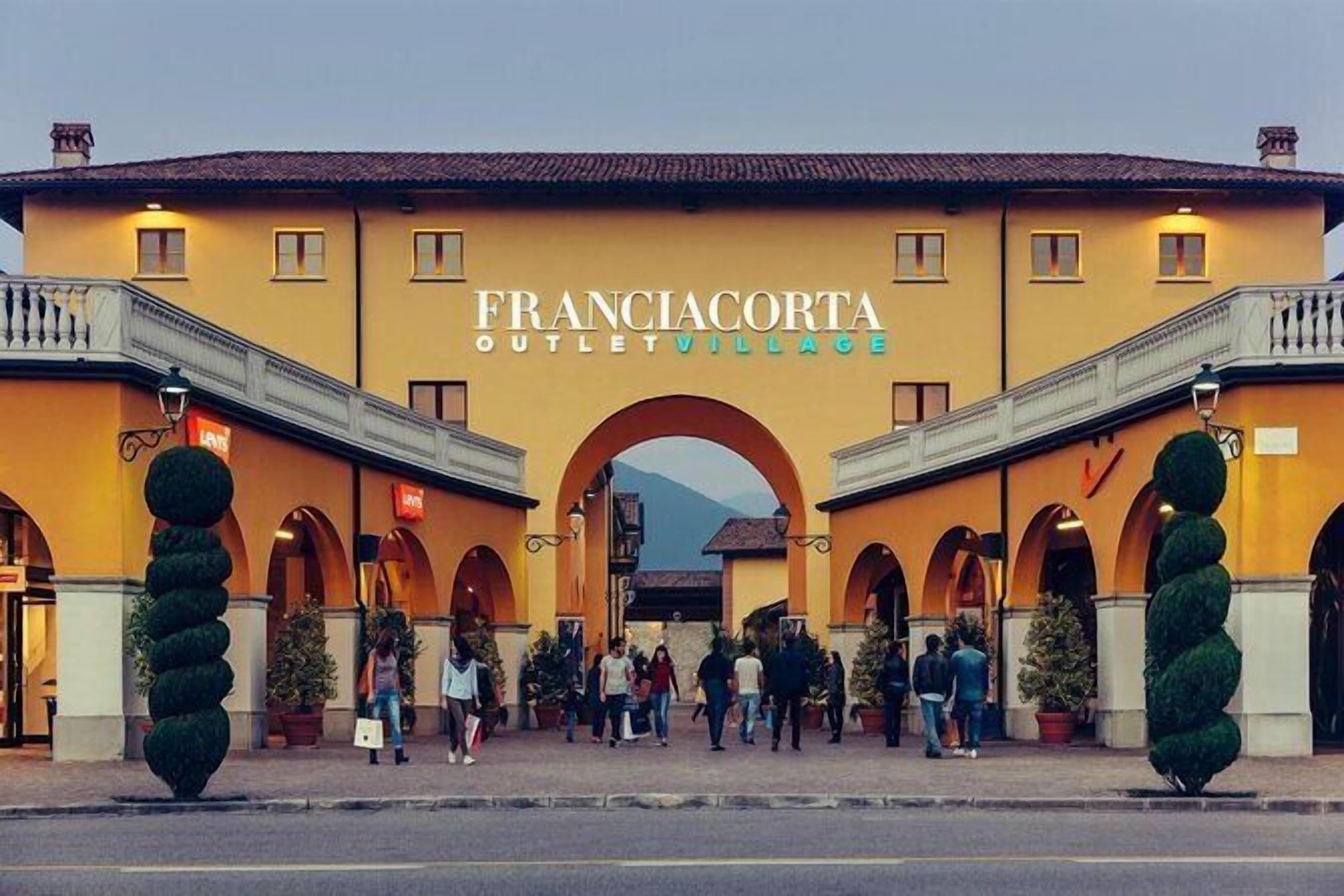Een gebouw met het bord 'FRANCIACORTA OUTLET VILLAGE' en meerdere bogen.