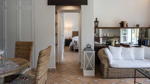 Ein gemütliches Wohnzimmer mit Rattanmöbeln, einem weißen Sofa und einem Esstisch.