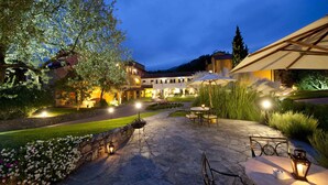 Eine Außenpatio-Terrasse mit Steinboden, Sitzgelegenheiten und stimmungsvoller Beleuchtung.