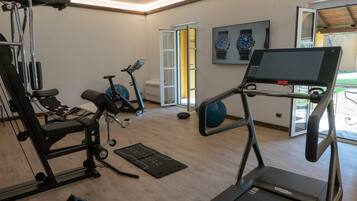 Ein Fitnessstudio mit Trainingsgeräten, Laufband und einer Tür, die nach draußen führt.