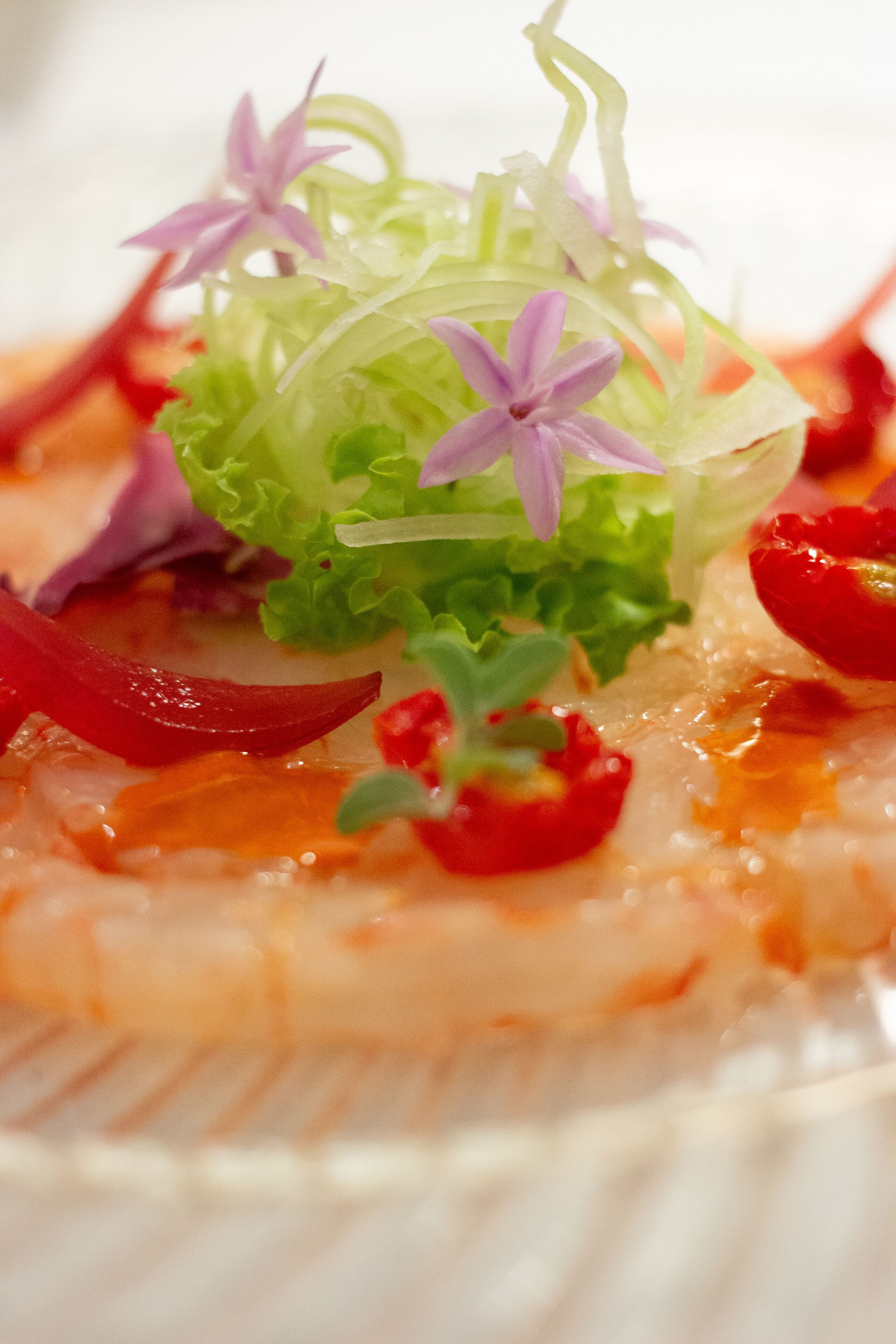Eine Nahaufnahme eines Fischgerichts mit Garnelen, roten Paprika und verschiedenen Garnituren.