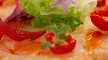 Eine Nahaufnahme eines Fischgerichts mit Garnelen, roten Paprika und verschiedenen Garnituren.