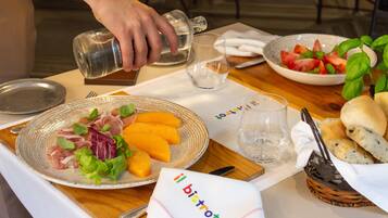 Una mesa servida con platos de comida, un vaso de agua y una cesta de pan.