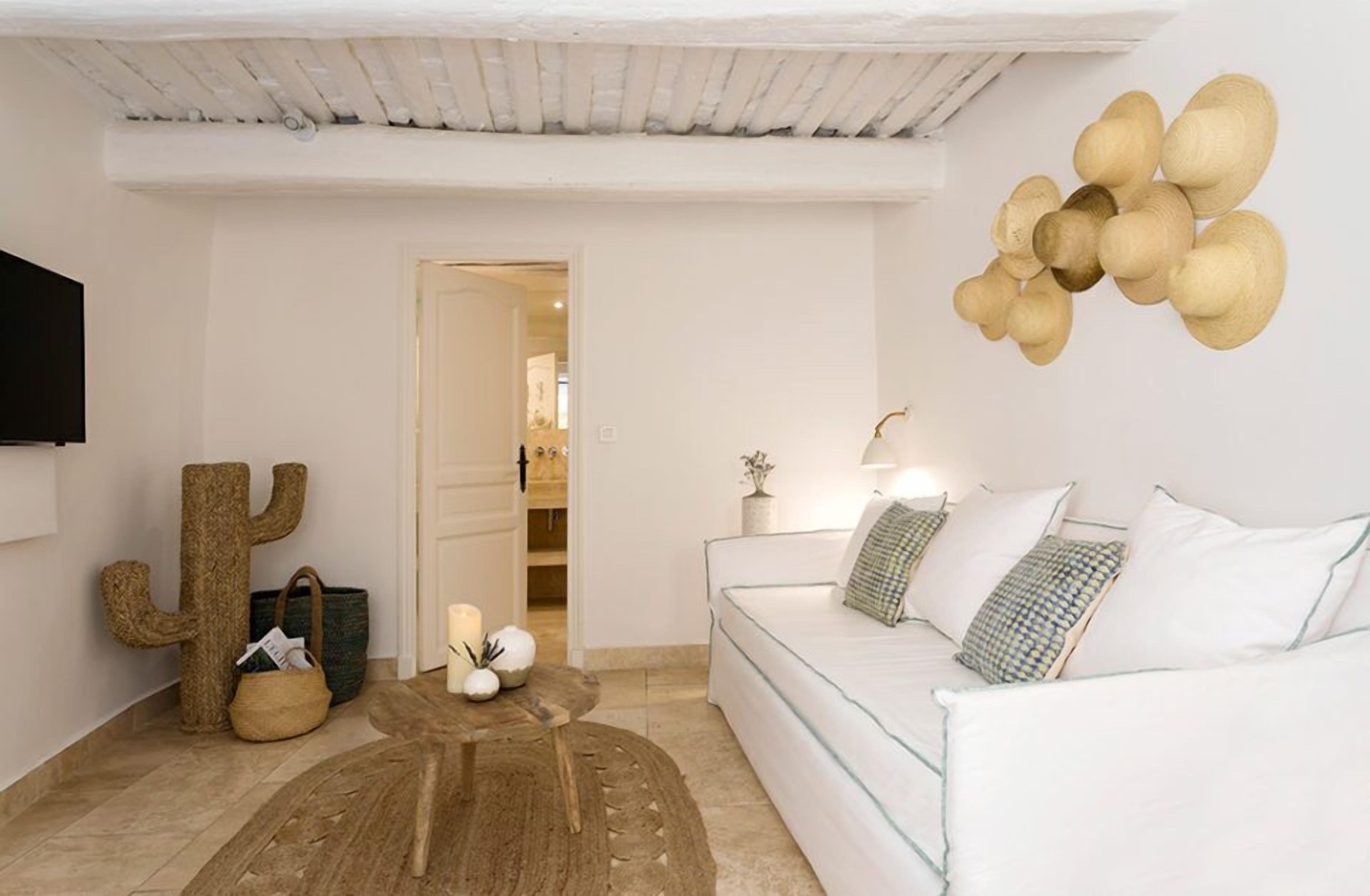 A modern living room with a white sofa, a cactus decoration, a wooden coffee table, and a wall-mounted light fixture.
