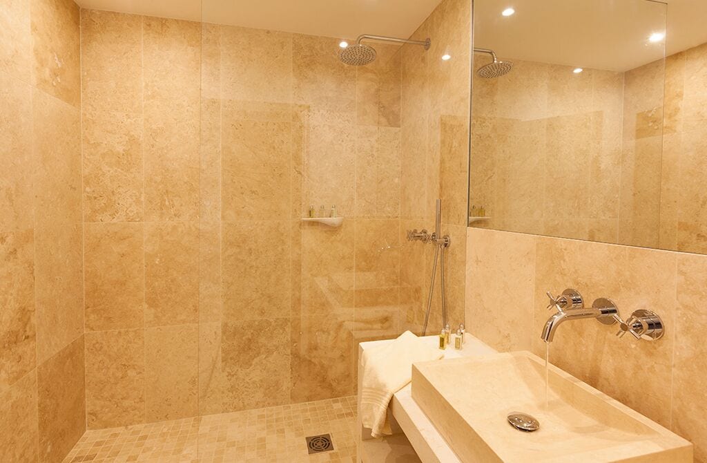 Un baño moderno con ducha envuelta en vidrio, tocador con lavamanos y espejo.