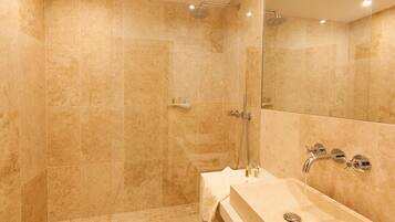 Un baño moderno con ducha envuelta en vidrio, tocador con lavamanos y espejo.