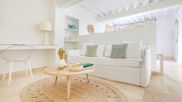 Ein modernes Wohnzimmer mit einem weißen Sofa, einem runden Holztisch und einem transparenten Glasstuhl.