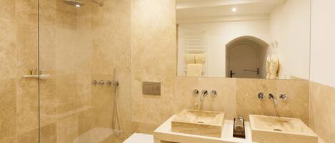 A modern bathroom with two sinks, a glass-enclosed shower, and a toilet.
