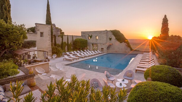 Zona junto a la piscina con sillones de descanso y vistas al atardecer.