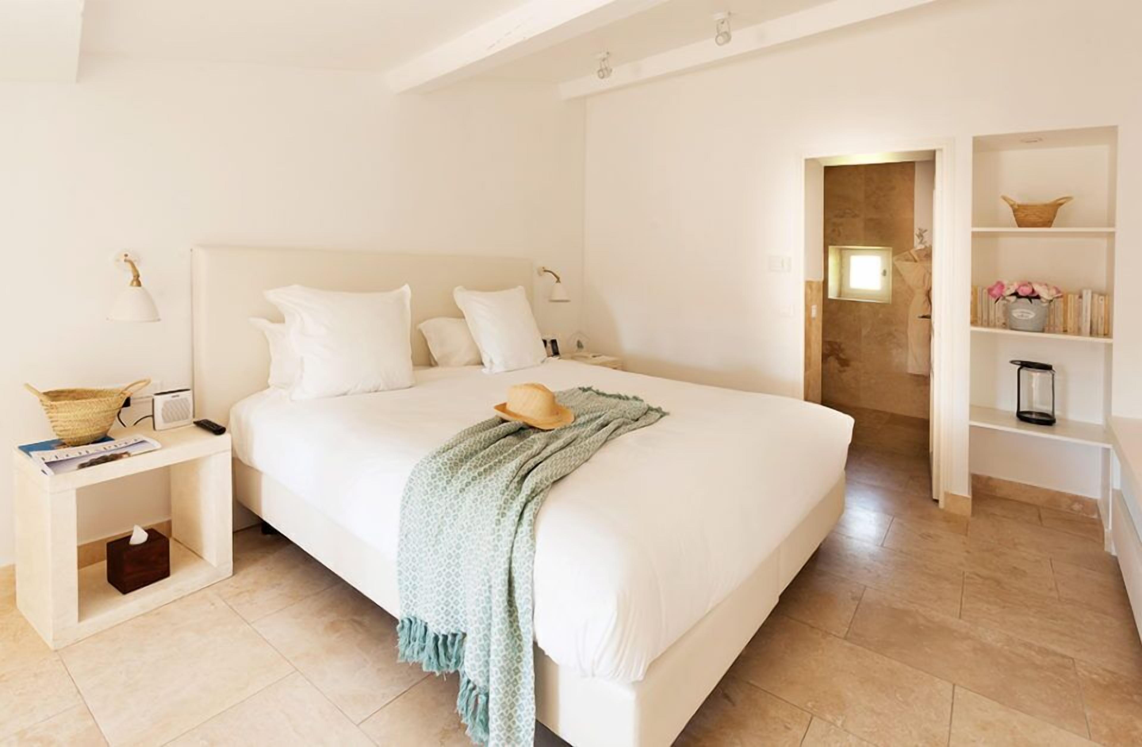 A spacious bedroom with a large bed, bedside tables, a nightstand, and a built-in bookshelf.