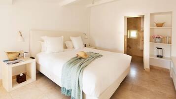 A spacious bedroom with a large bed, bedside tables, a nightstand, and a built-in bookshelf.