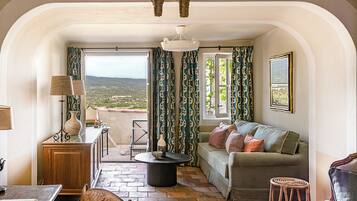 A cozy living room with a sofa, a dining table, and a view of the countryside.
