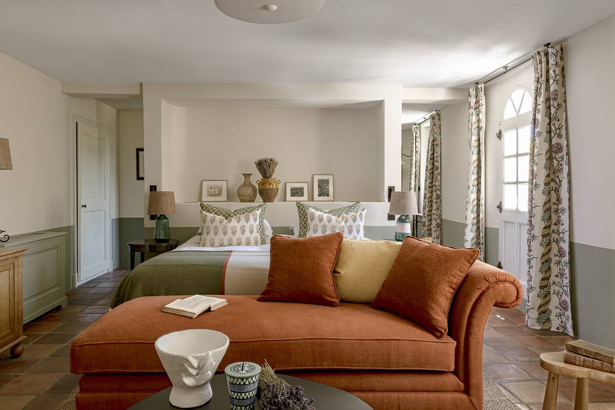 Een hotelkamer met een groot bed, een bank, een tafel met een vaas en een lamp.