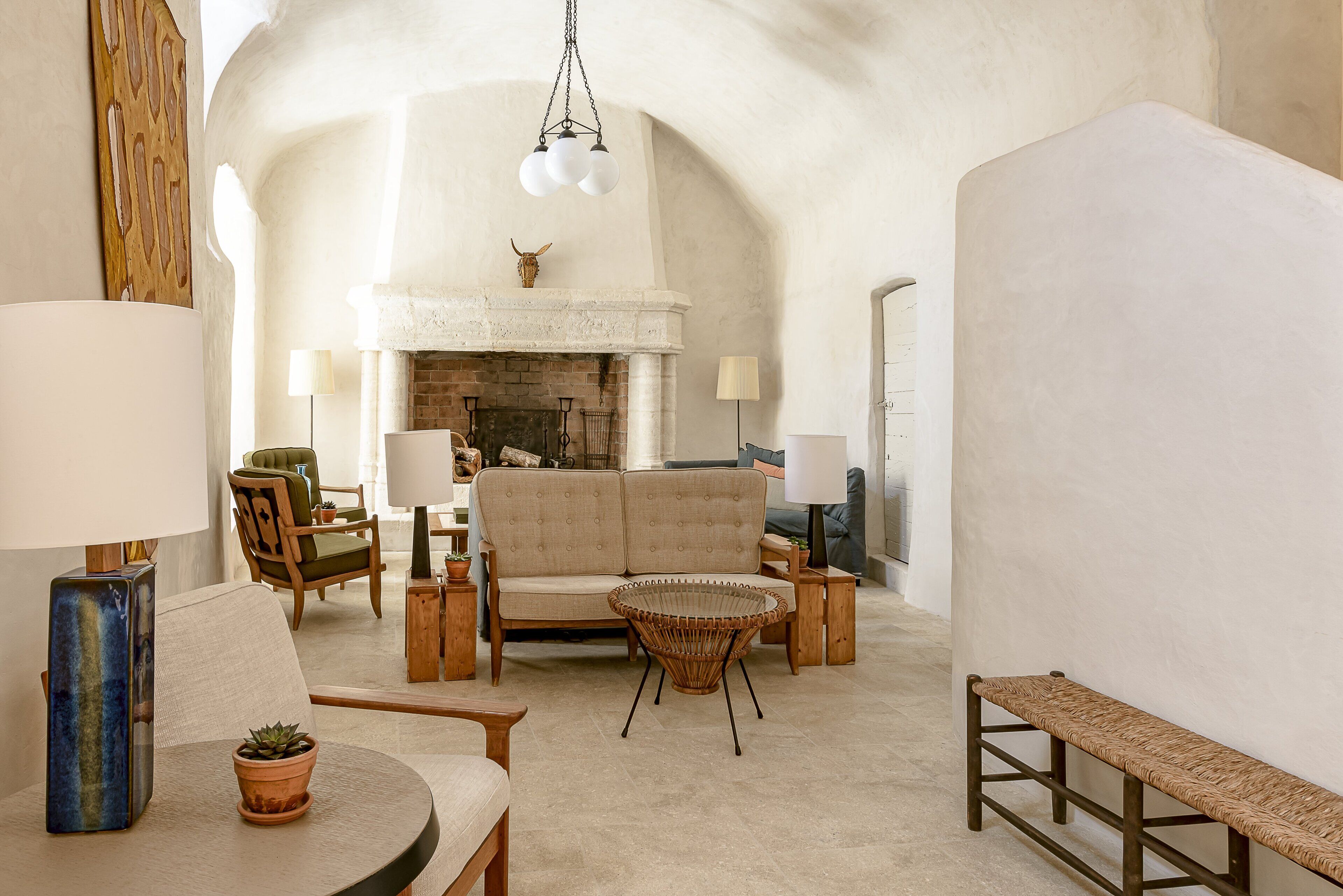 A spacious living room with a fireplace, comfortable seating, and a high arched ceiling.