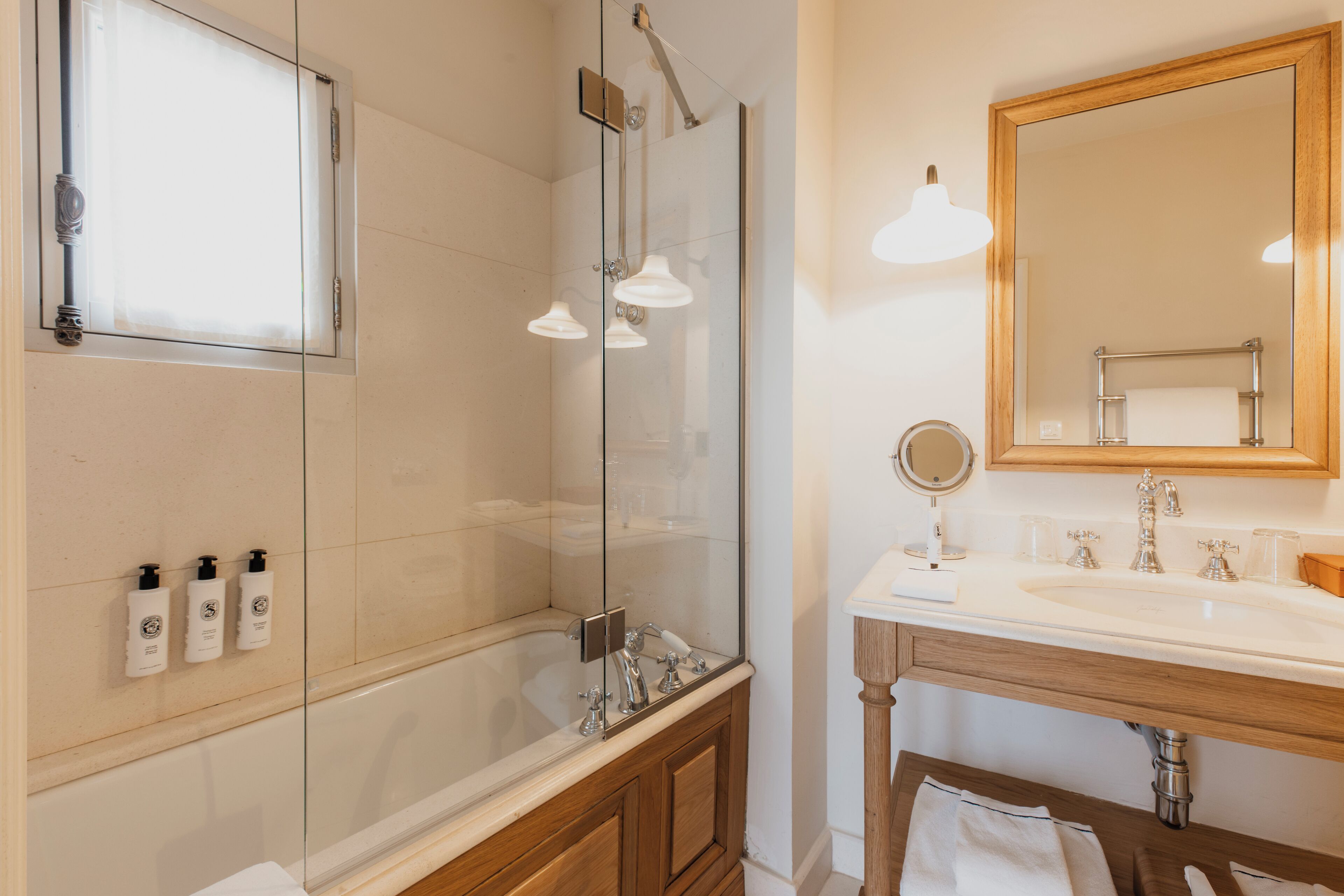 Une salle de bain moderne dotée d’une douche à parois de verre, d’un meuble-lavabo en bois et d’un grand miroir placé au-dessus du meuble-lavabo.