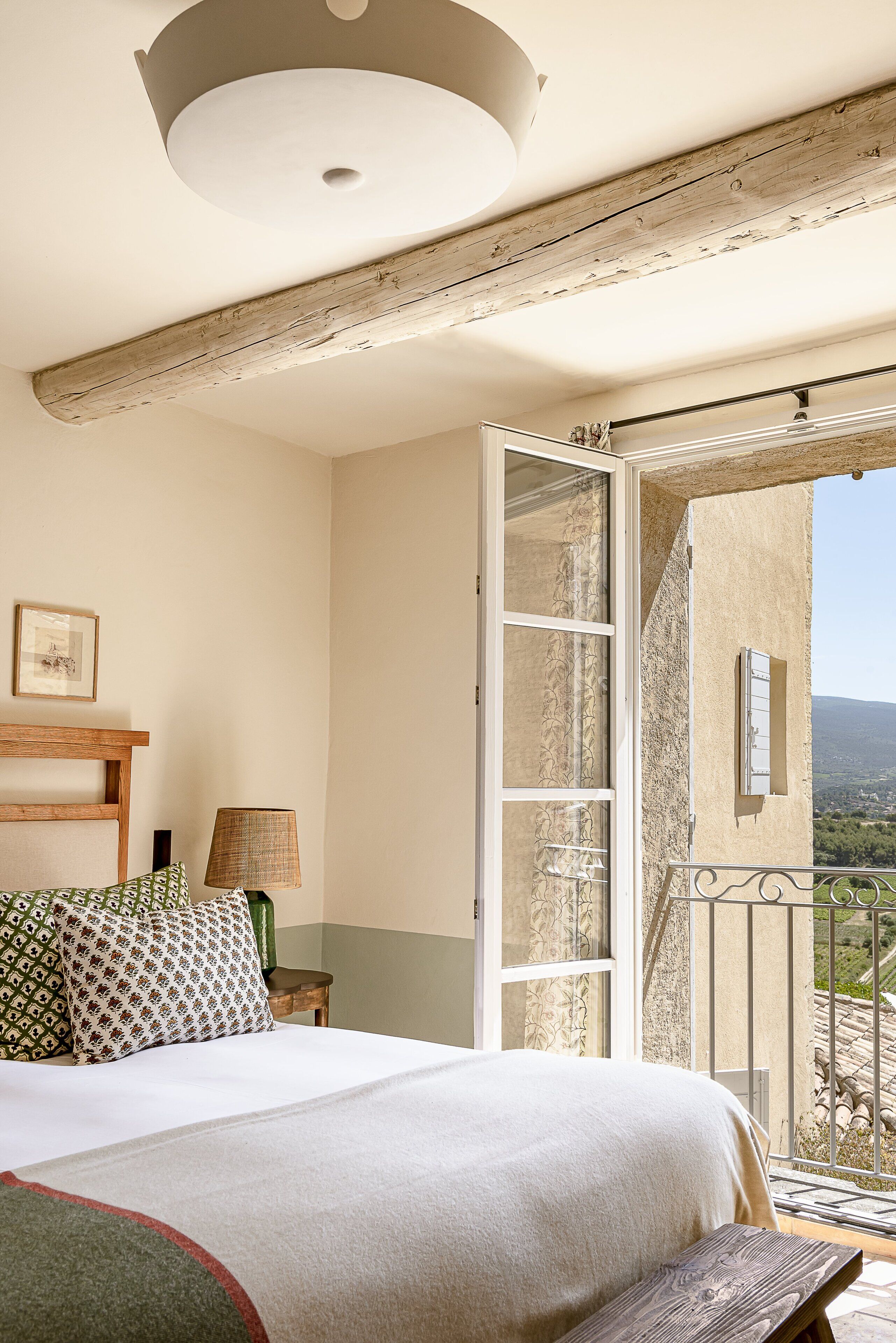 Ein Schlafzimmer mit Bett, Nachttisch, Lampe und Blick ins Freie.