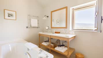 Un baño moderno con lavamanos doble, un espejo grande y una bañera.