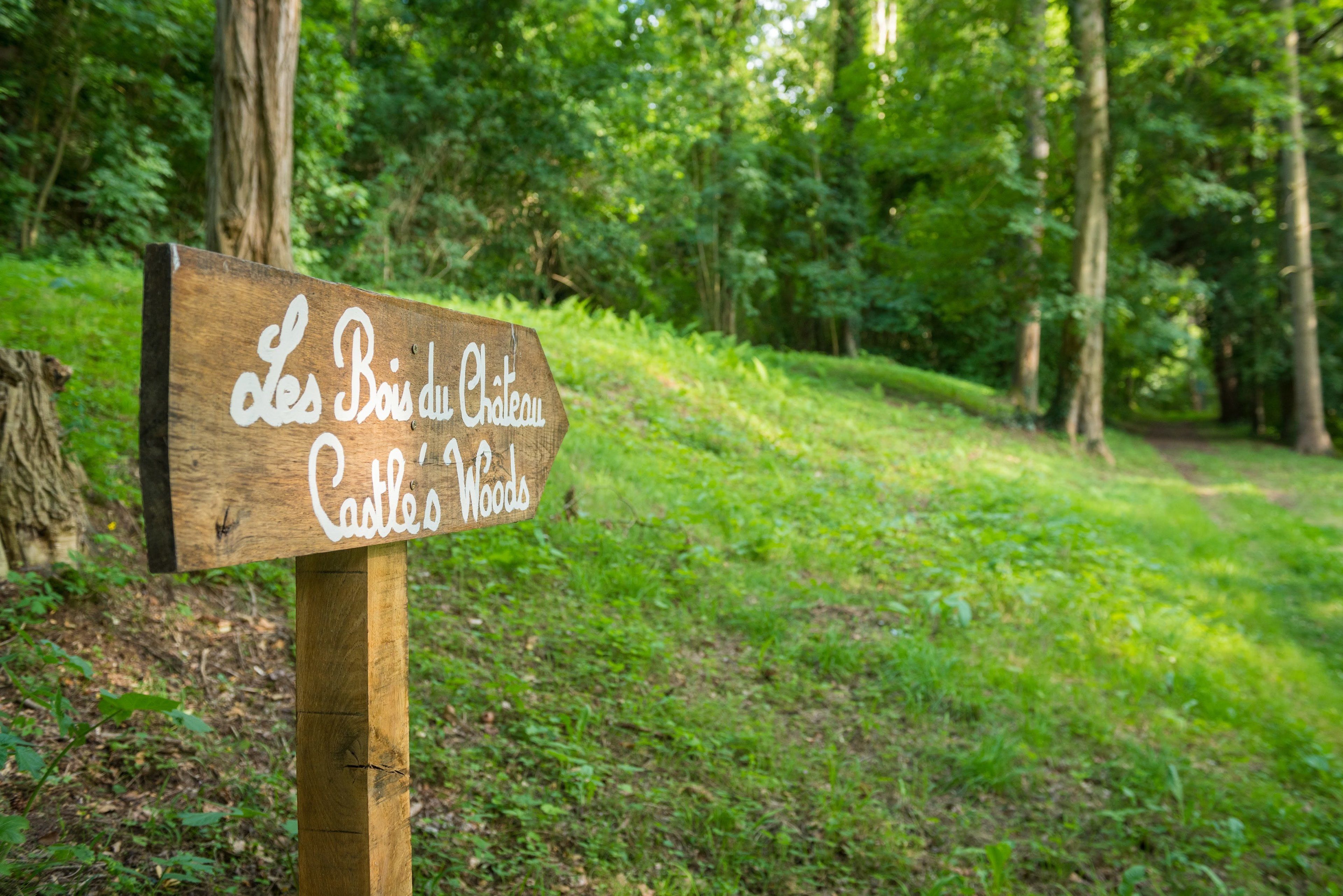 A wooden sign with the text "Les Bois du Chateau Castles Woods".