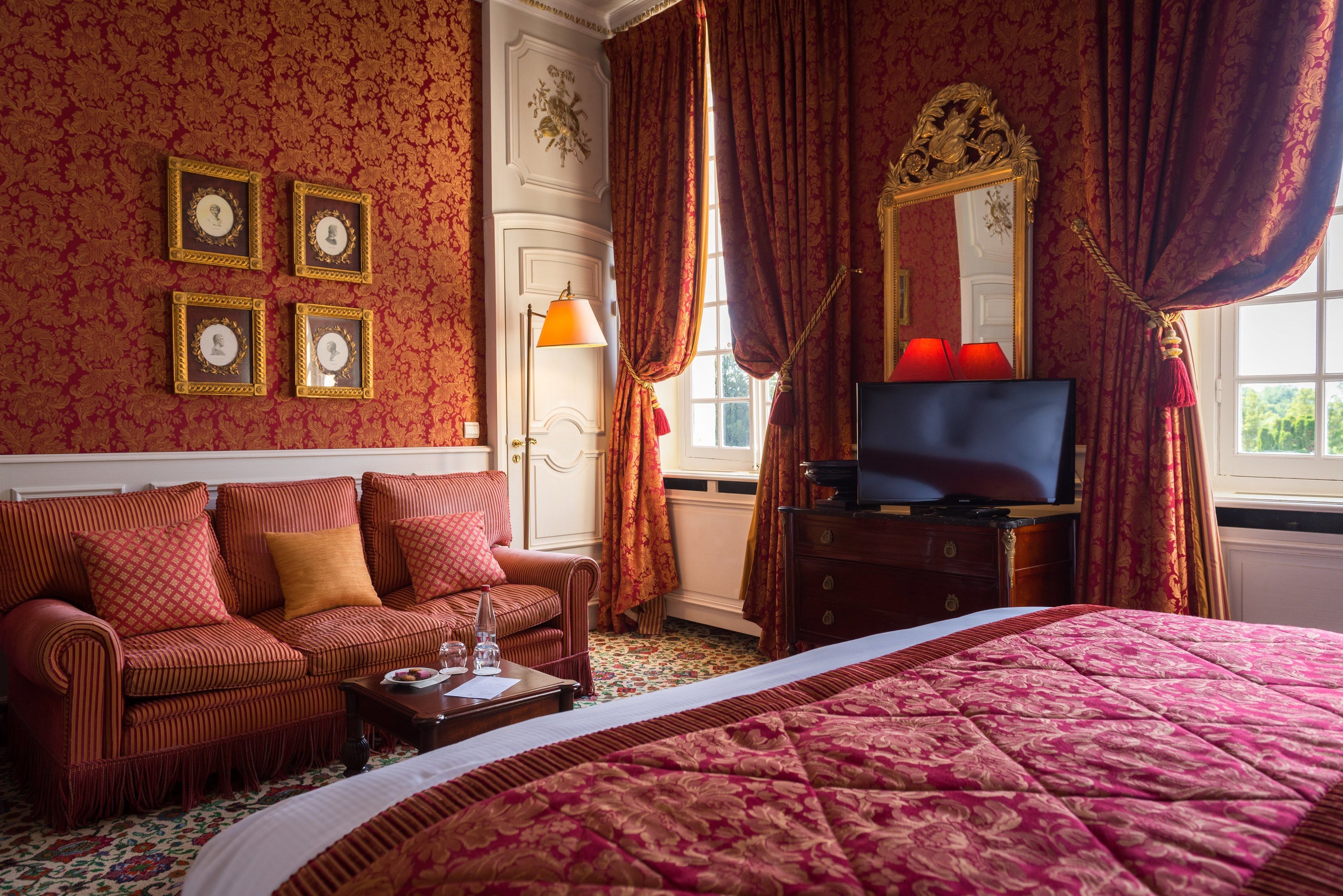 Una habitación de hotel con una cama grande, un sofá, un televisor y un aparador.