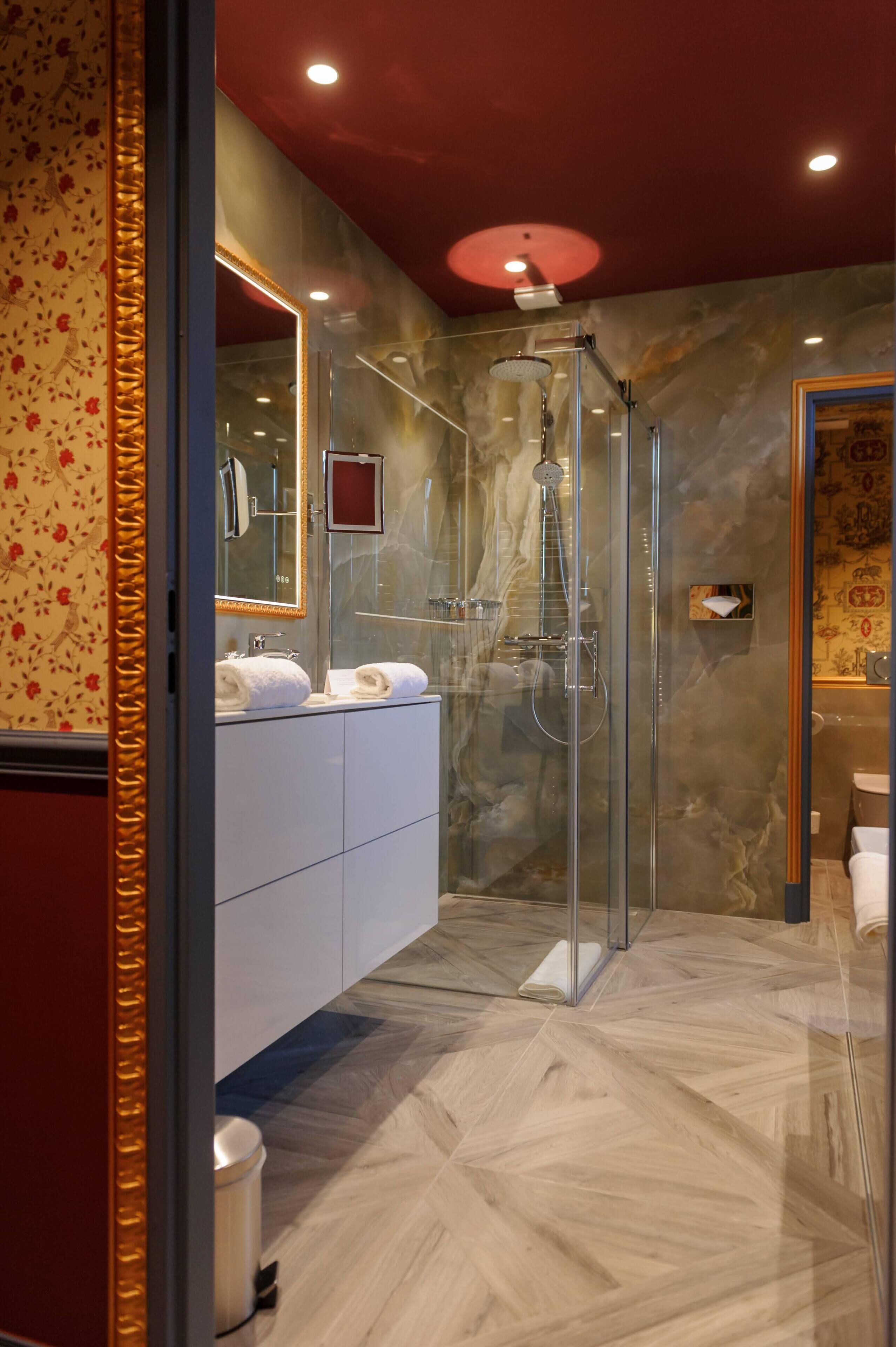 Un baño moderno con ducha de vidrio, tocador blanco y piso de mármol.