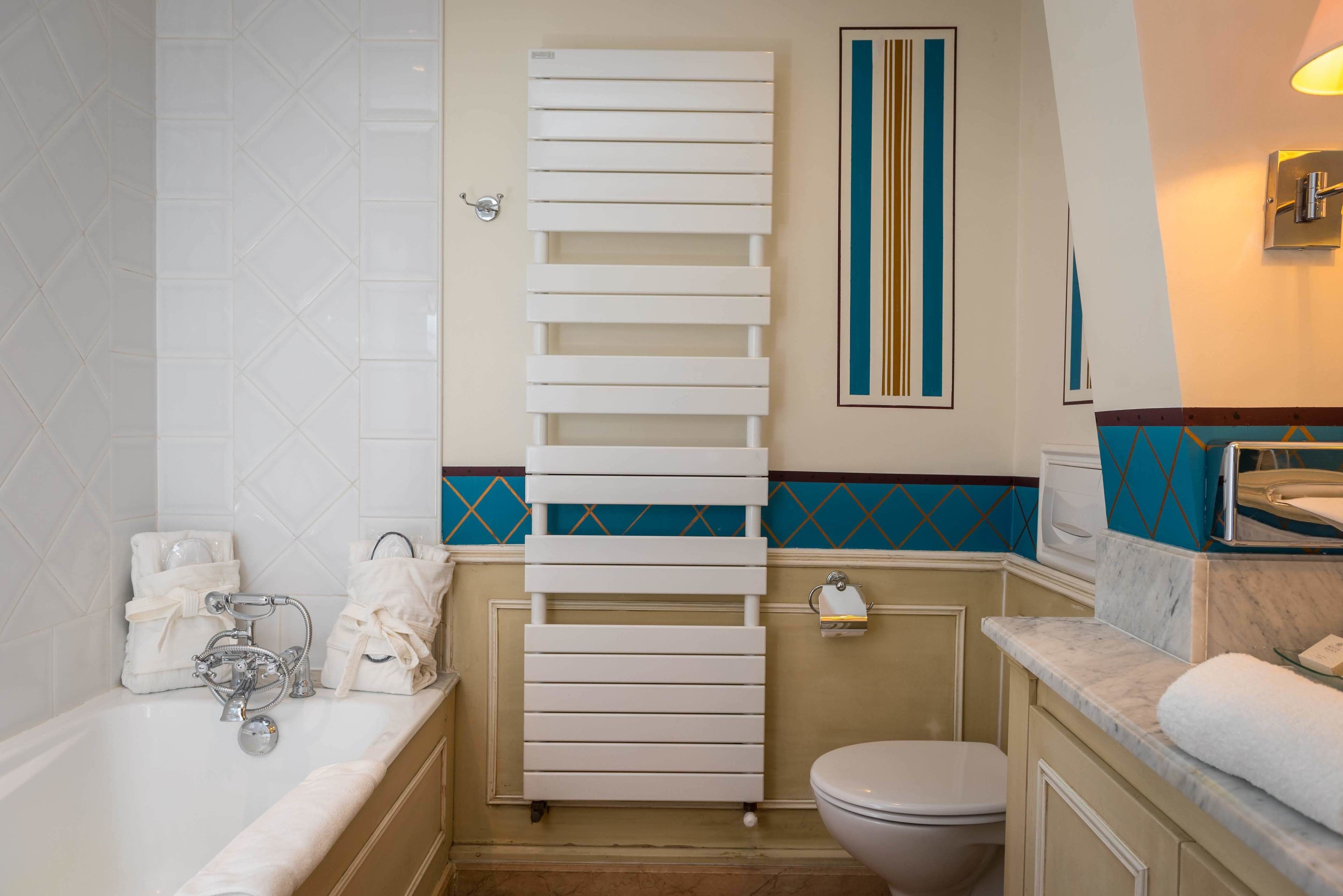 A bathroom with a bathtub, toilet, and a towel rack.