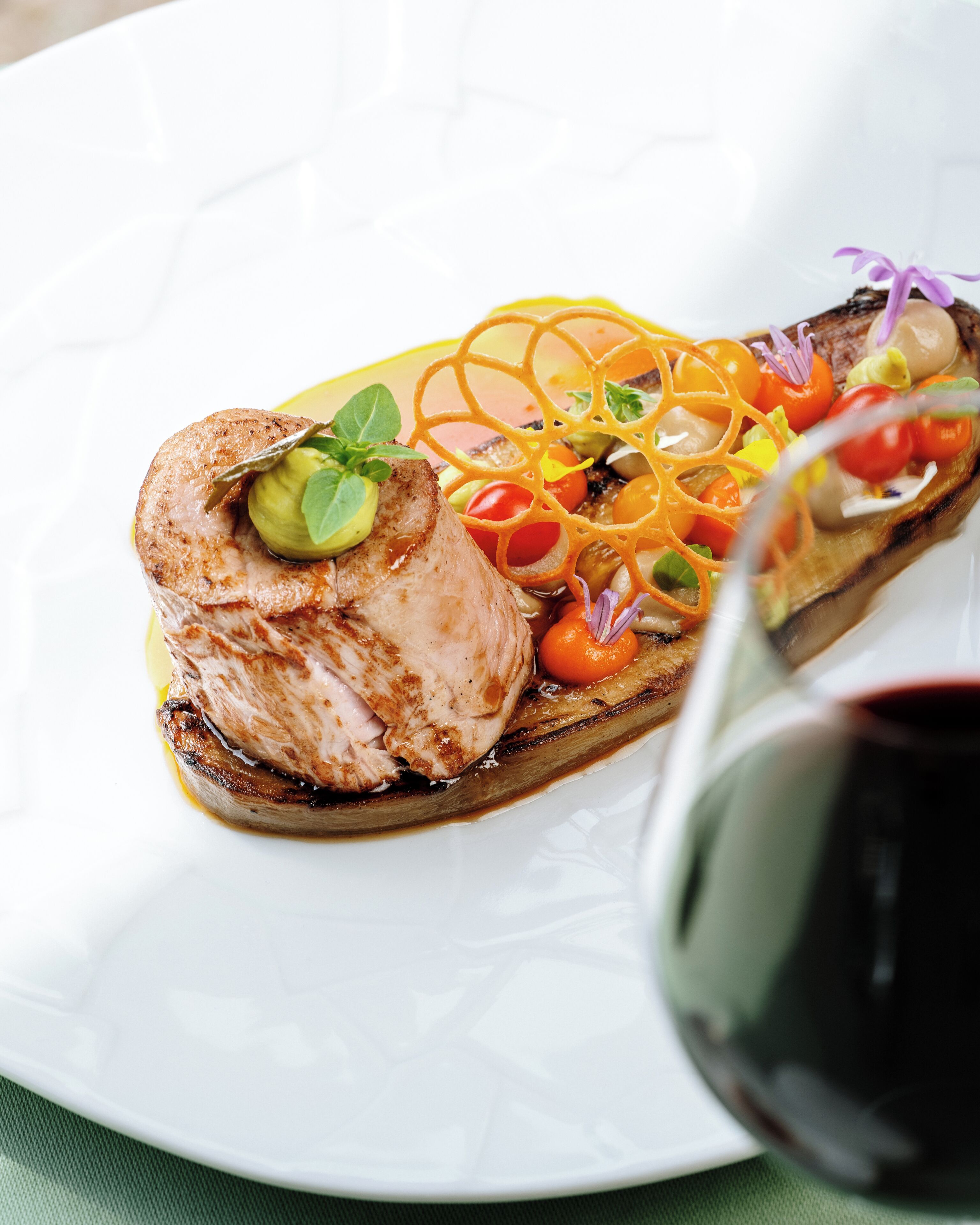 A plate of food with a piece of meat, vegetables, and a sauce.