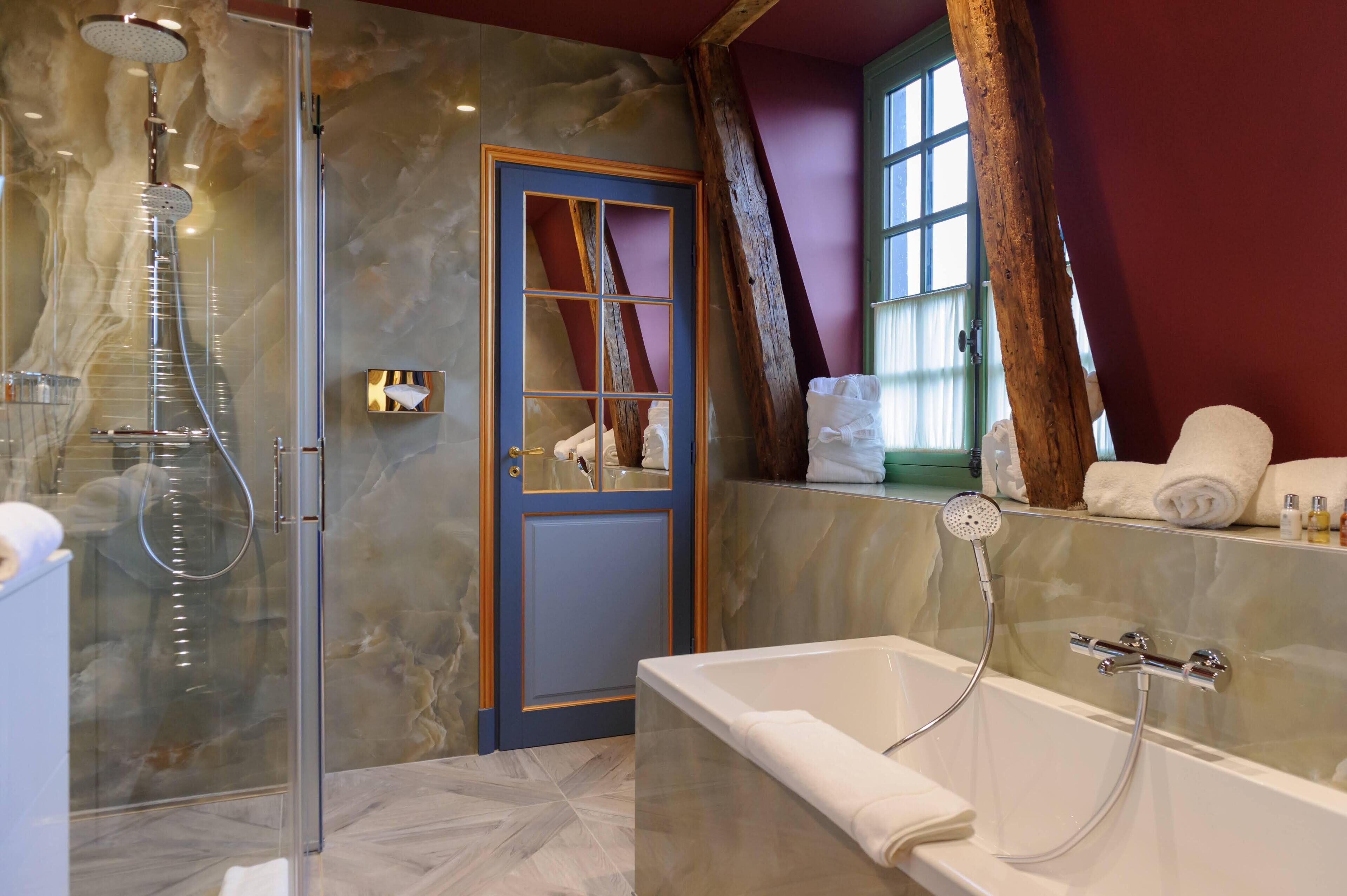A modern bathroom with a glass-enclosed shower, a bathtub, and a vanity with toiletries.