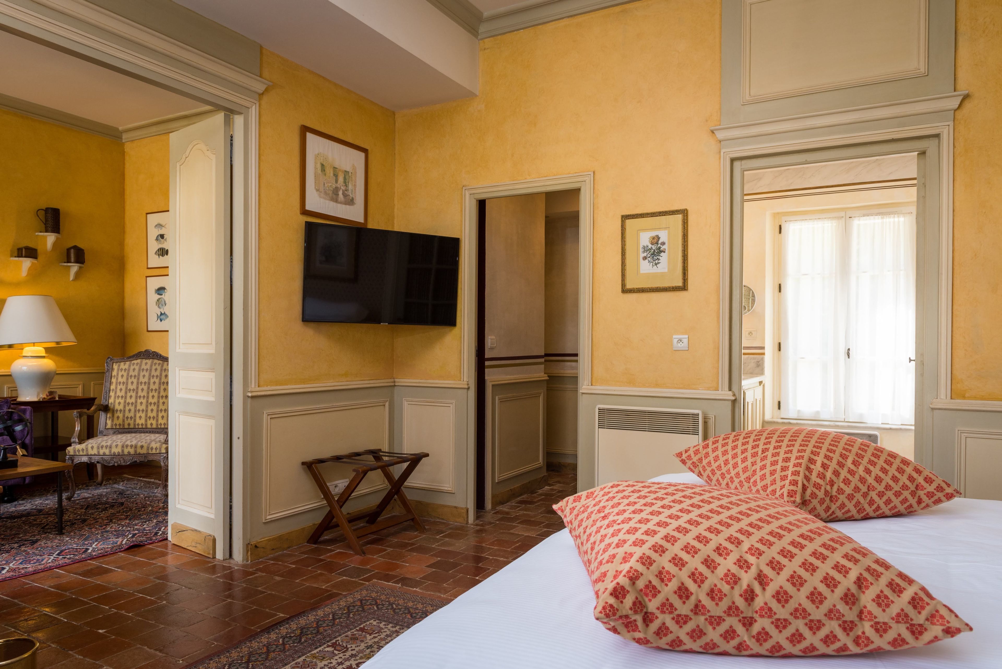 A hotel room with a bed, a television, a small table, and a chair.