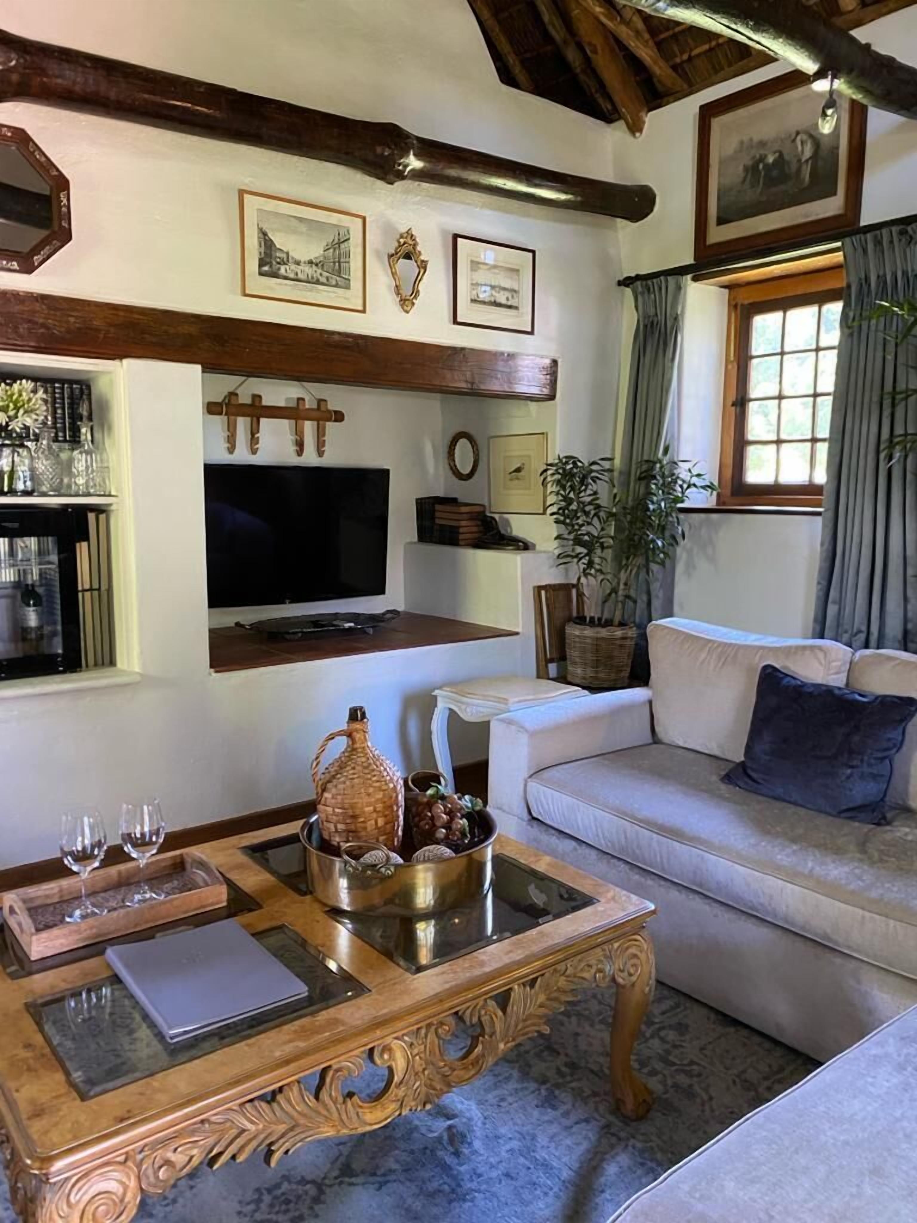 A cozy living room with a wooden coffee table, a flat-screen TV, a sofa, and a window with curtains.