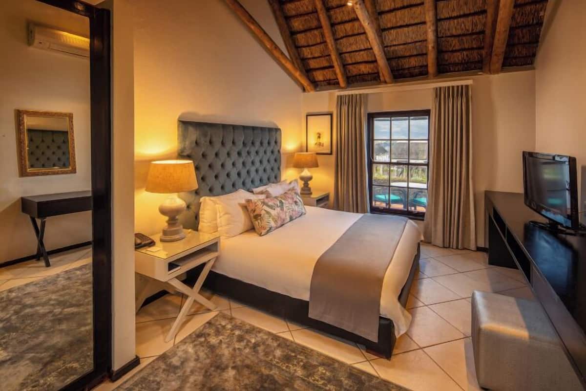Une chambre d’hôtel avec un grand lit, une télévision, un bureau et une fenêtre avec des rideaux.