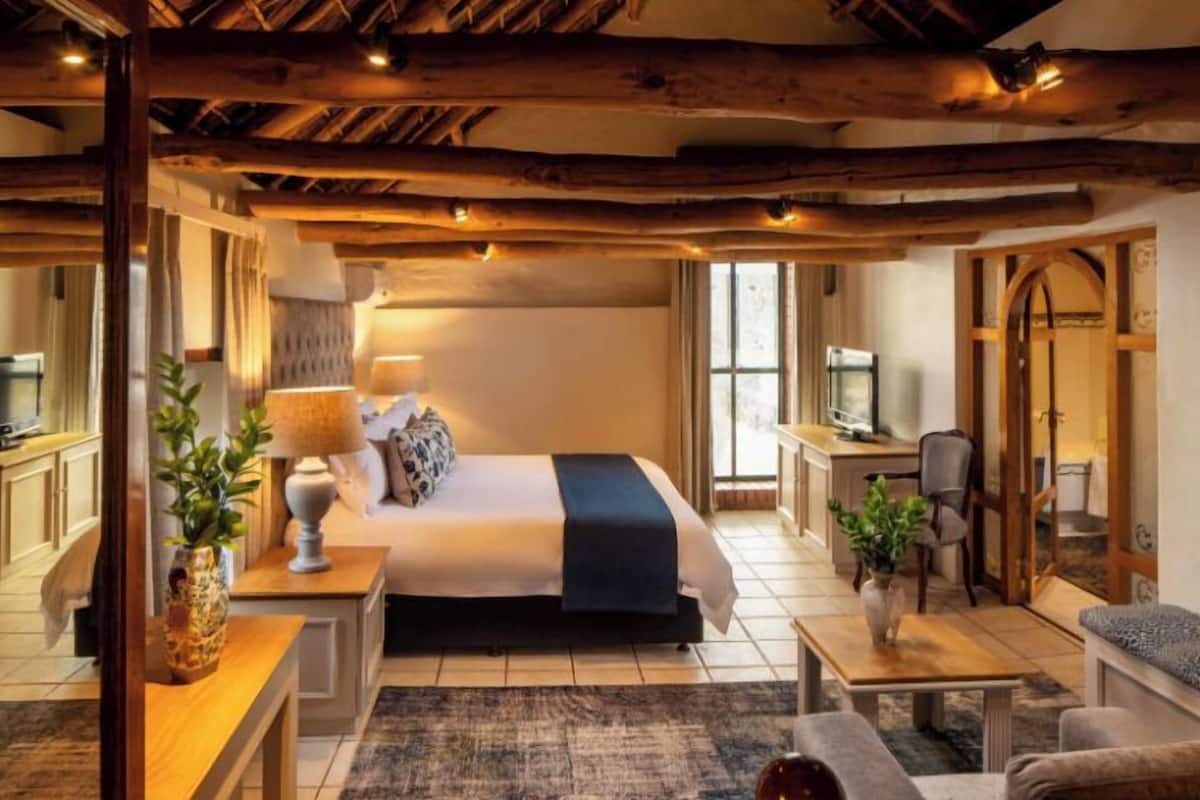 Une chambre confortable avec un grand lit, des tables de chevet, un bureau et une chaise. On y trouve également une télévision et une fenêtre avec des rideaux.